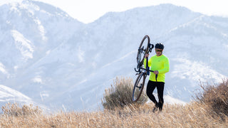 Person holding a bicycle in a mountainous landscape